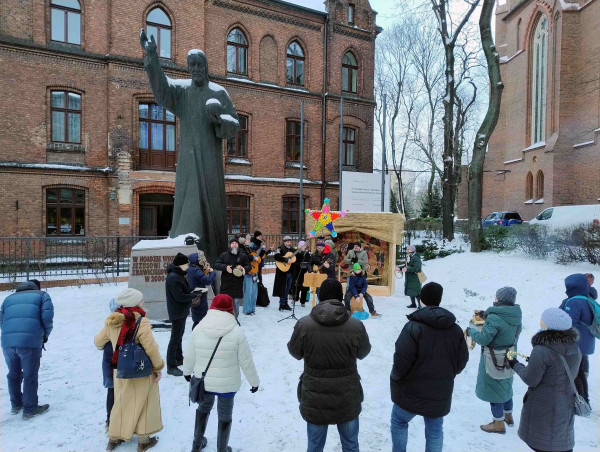 Śpiewanie kolęd przy szopce na zewnątrz kościoła