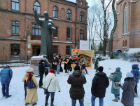 Śpiewanie kolęd przy szopce na zewnątrz kościoła